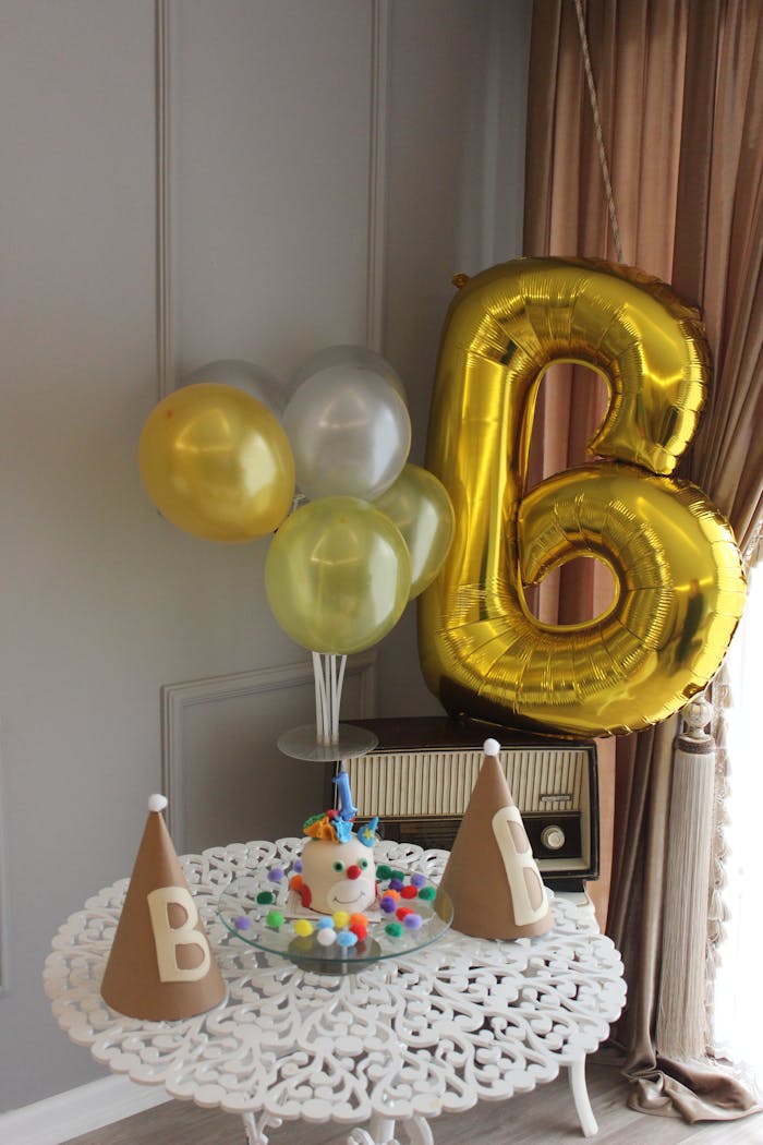 Festive birthday setup with balloons, cake, and party hats on a table. Perfect for celebrations.