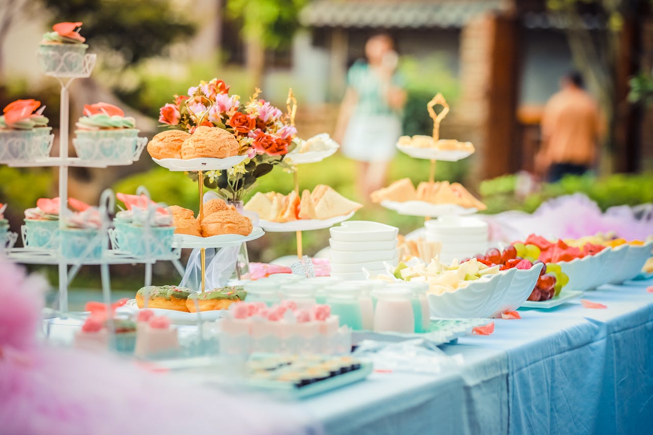 hero-img-02 A vibrant outdoor buffet table showcasing an array of colorful pastries and fruits, perfect for parties.